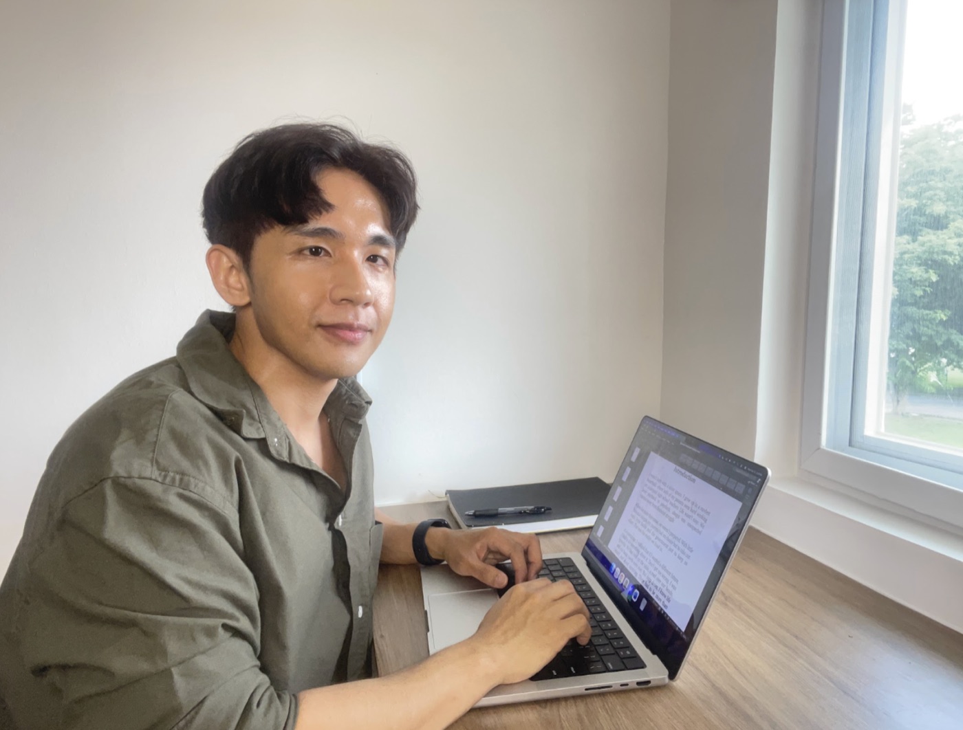 Quin Diaz working at a laptop beside a window.